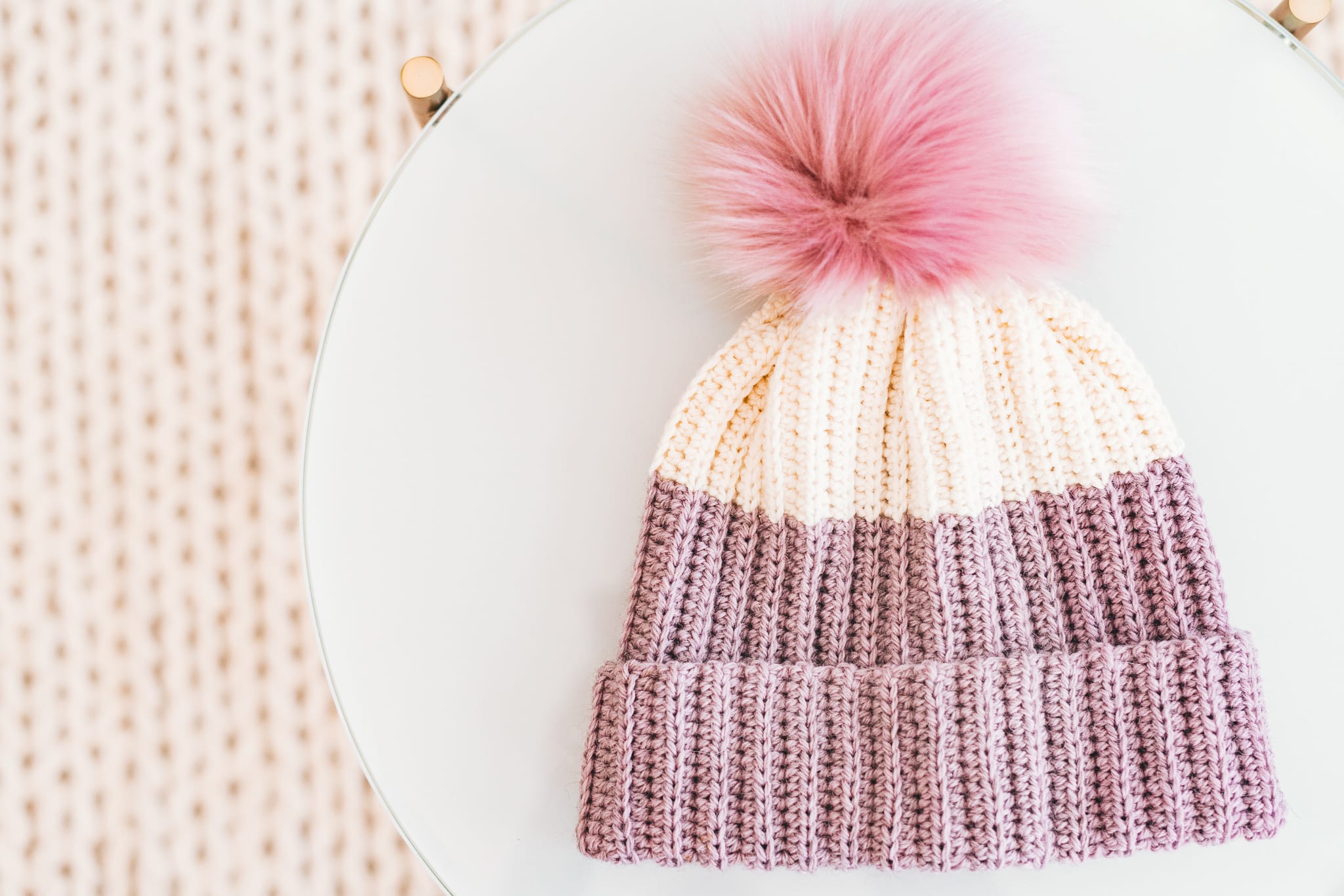 Crochet hat with knit look fabric and a faux fur pom pom